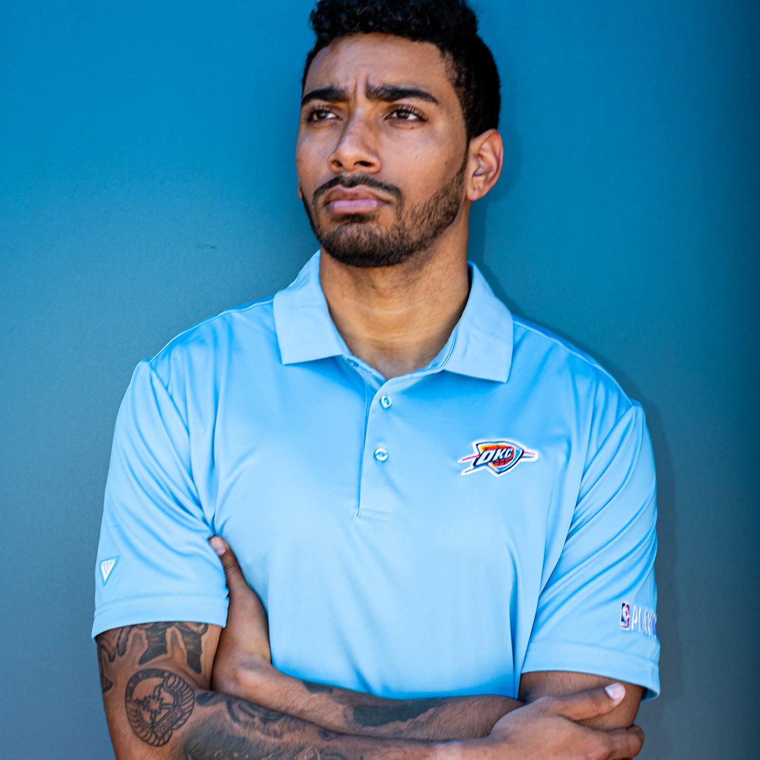 Man standing with arms folded in a blue polo