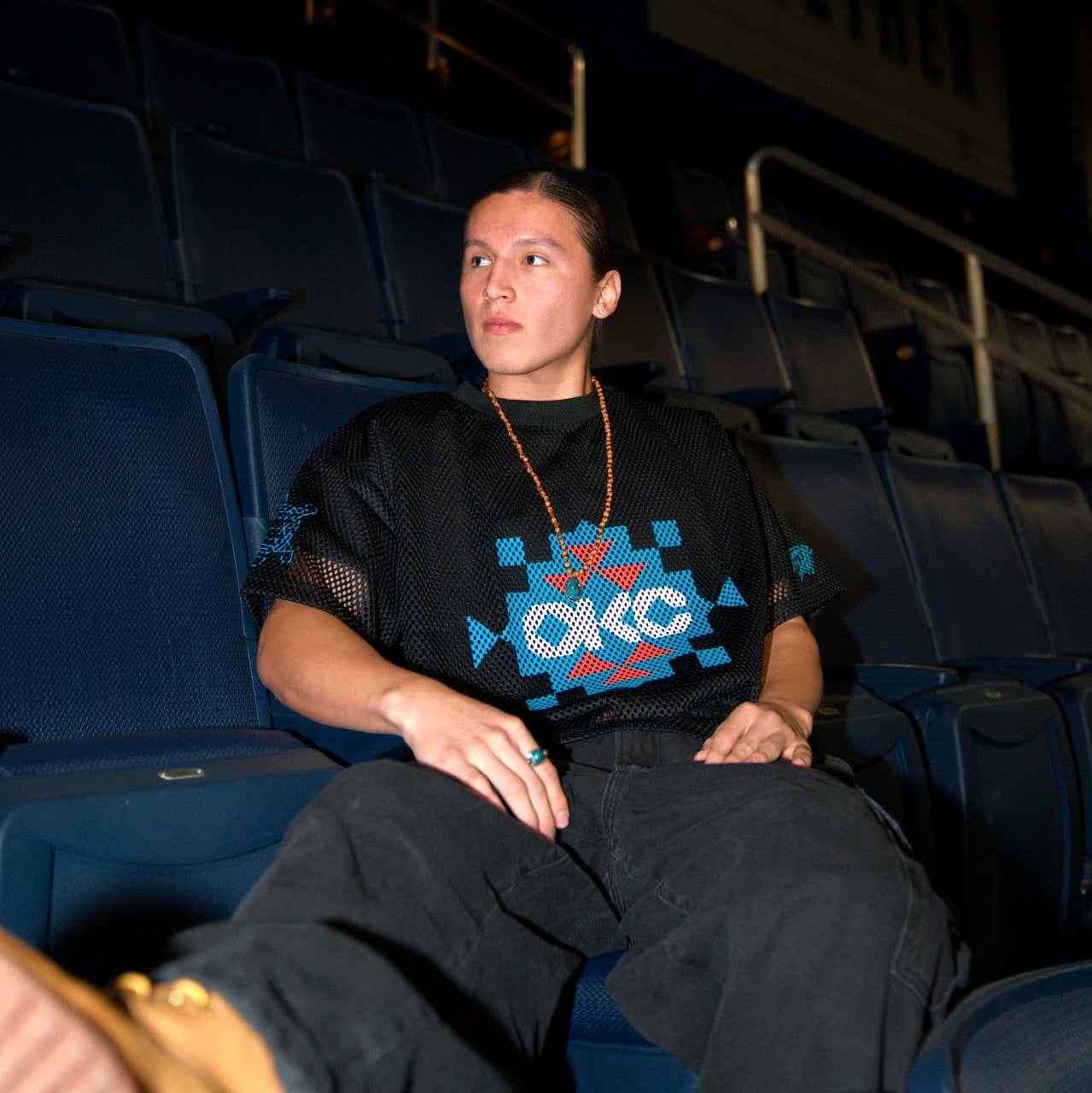 Person sitting in a dark theater with blue seats